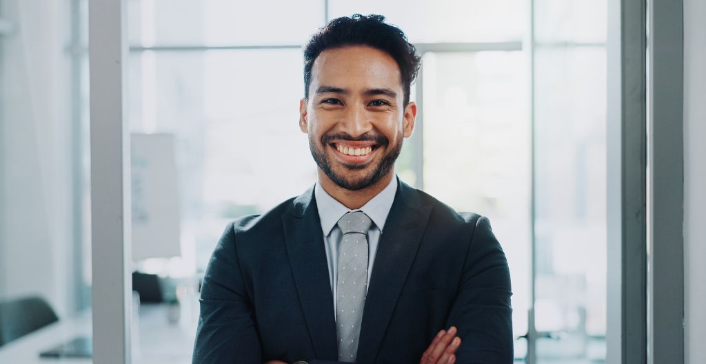 Smiling business professional with crossed arms wearing a suit and tie